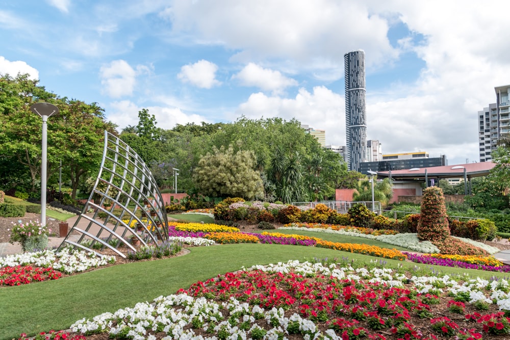garden with flowers and trees near high rise building during daytime