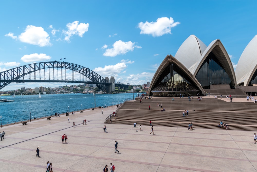 Persone che camminano sulla spiaggia vicino al Teatro dell'Opera di Sydney durante il giorno