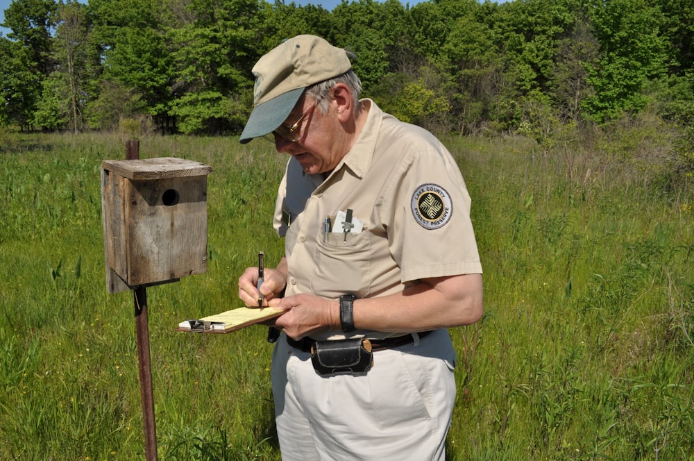 man in green shirt and brown hat holding brown wooden stick