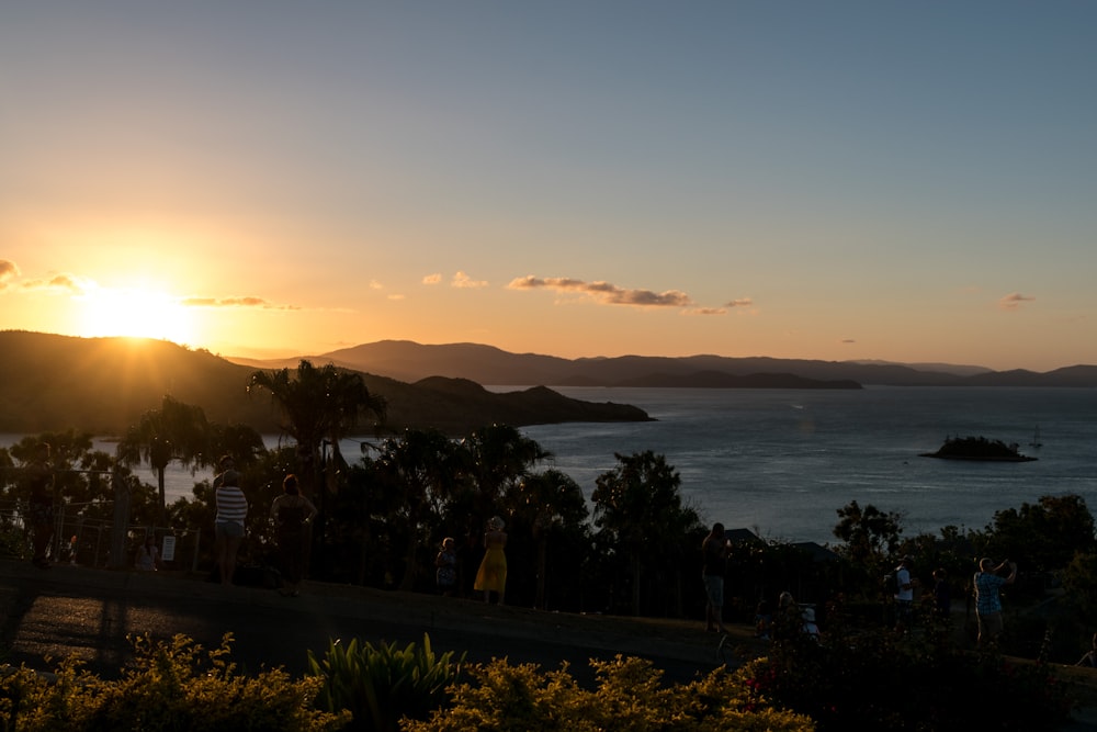 silhouette de personnes debout sur le bord de la mer pendant le coucher du soleil