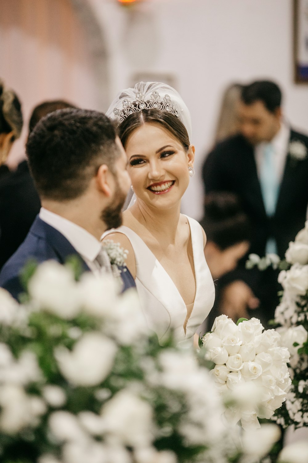 lächelnde Frau im weißen Hochzeitskleid neben Mann im schwarzen Anzug