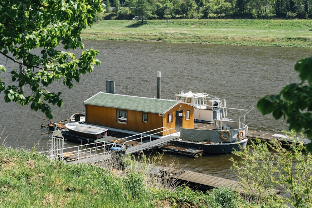 brown wooden house on green grass field near body of water during daytime