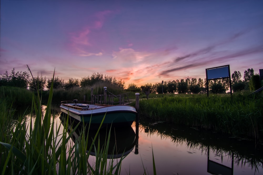 white boat on lake during sunset