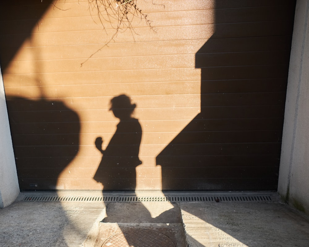 man in black jacket standing in front of brown wooden wall during daytime