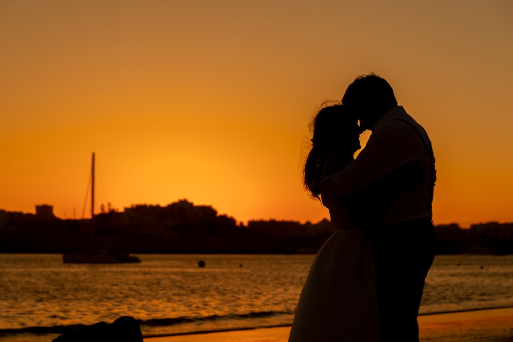 silhouette of man and woman kissing during sunset