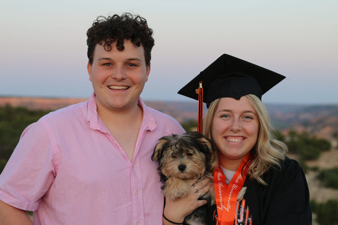 A young man in a pink shirt holding his small long-coated dog close to him
