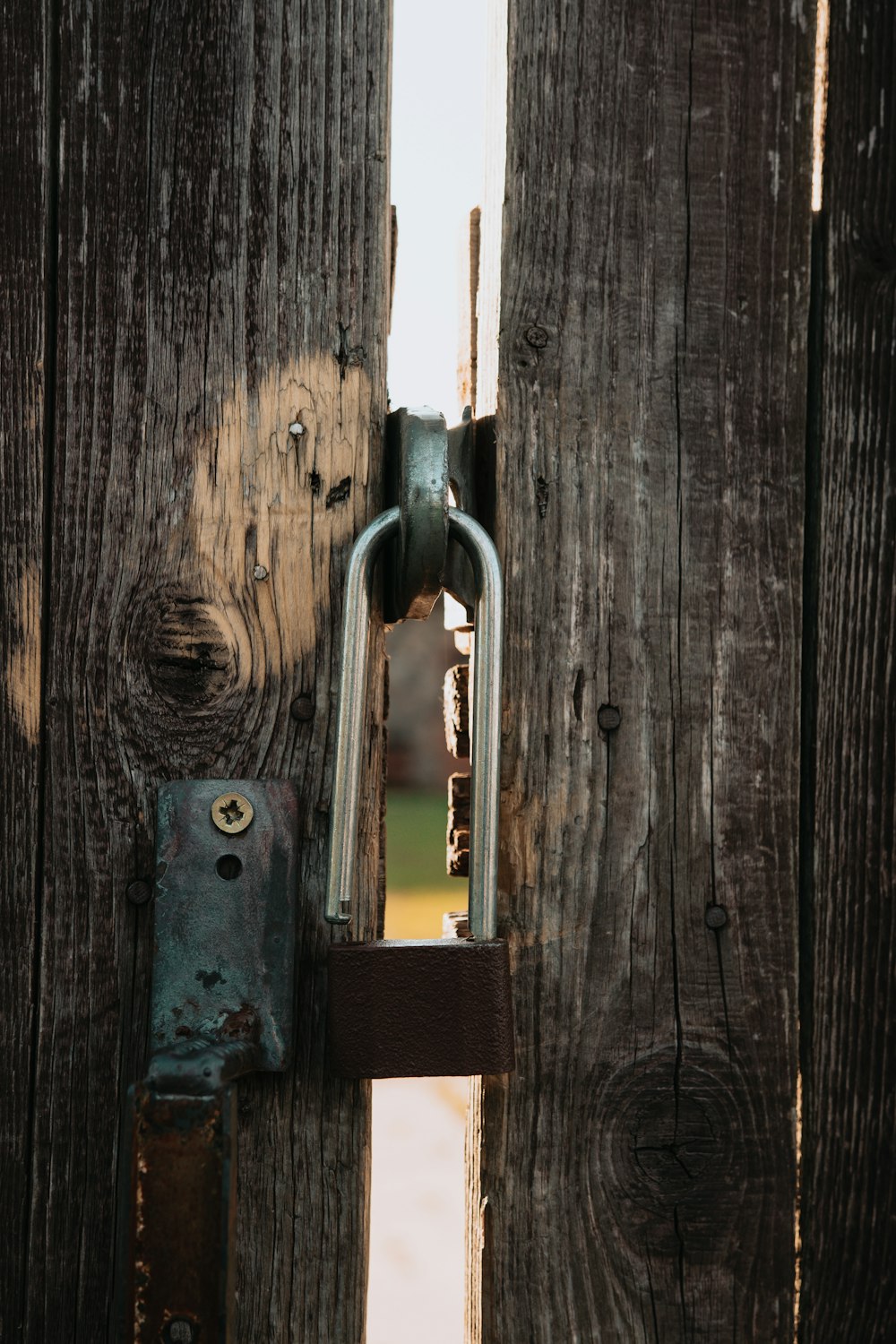 gray metal padlock on brown wooden door