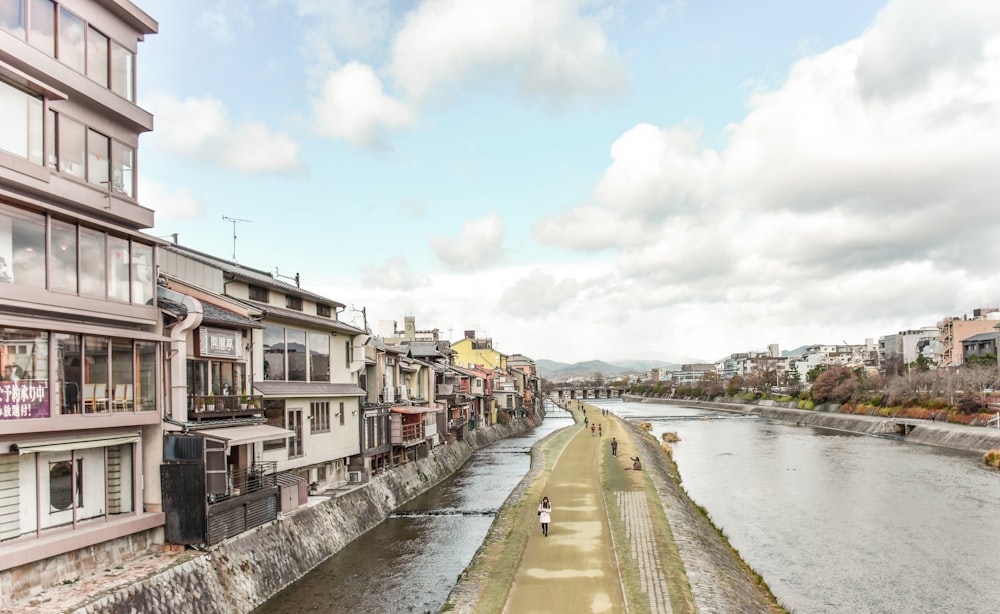 white and brown concrete building beside river under white clouds during daytime