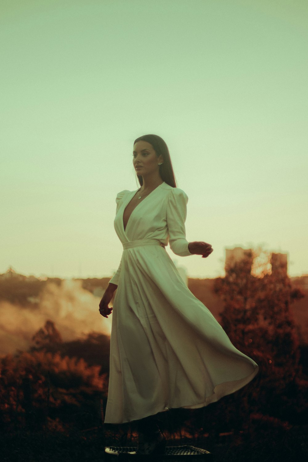 mulher no vestido branco da manga comprida que está em pé no campo da flor vermelha durante o dia