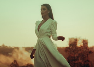 woman in white long sleeve dress standing on red flower field during daytime