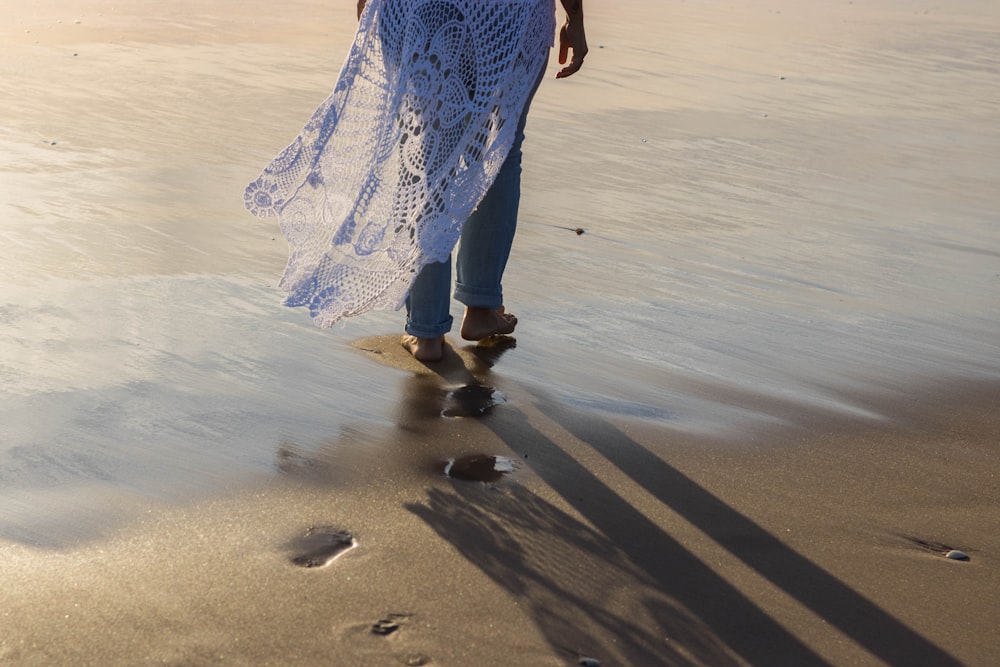woman in blue and white dress walking on beach during daytime