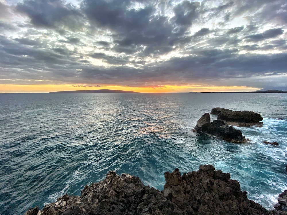 brown rocky shore under white clouds during daytime