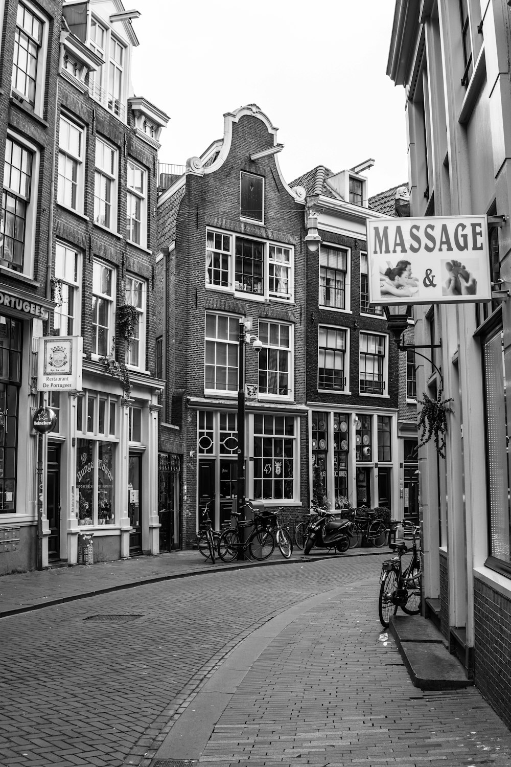 grayscale photo of man riding bicycle in front of building