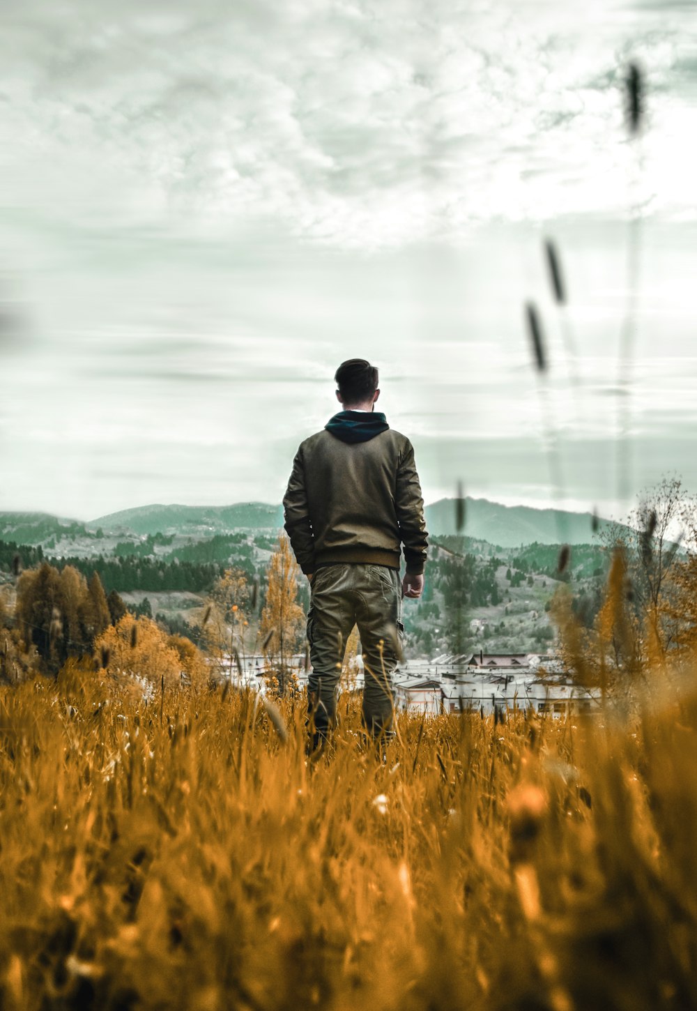 homem na jaqueta preta em pé no campo de grama marrom durante o dia