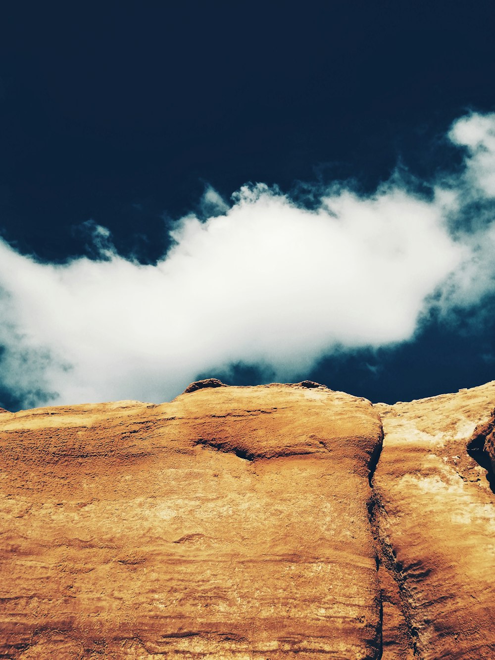 brown rock formation under white clouds