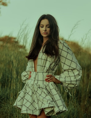 woman in white and black stripe dress standing on green grass field during daytime