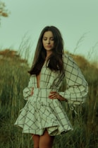 woman in white and black stripe dress standing on green grass field during daytime