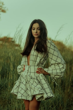 woman in white and black stripe dress standing on green grass field during daytime