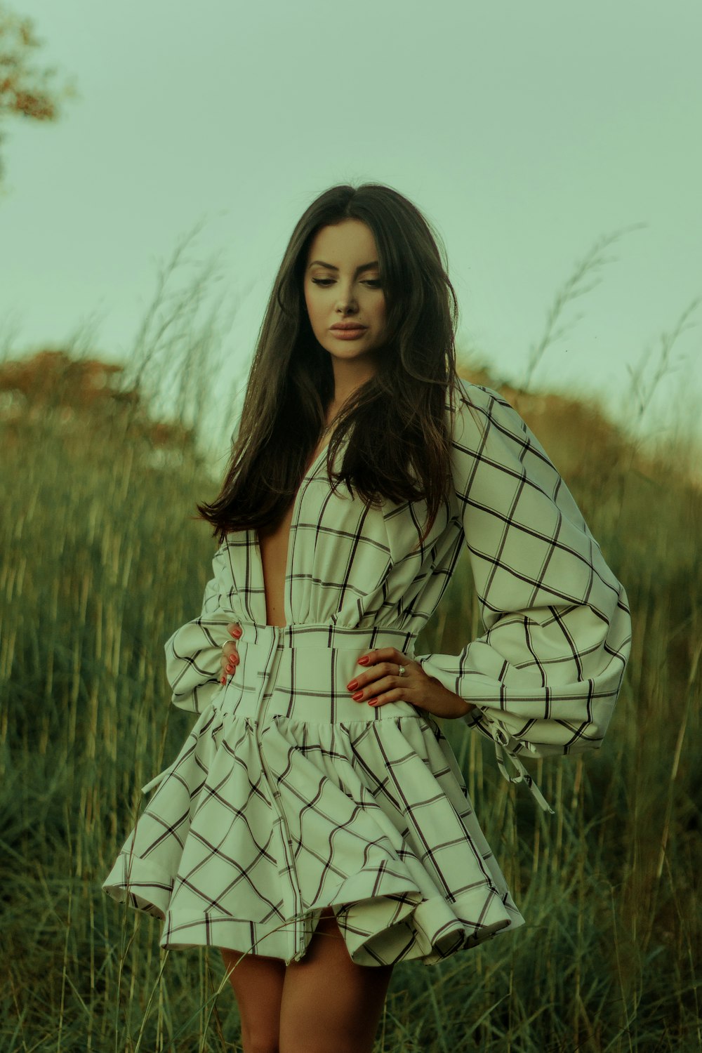 woman in white and black stripe dress standing on green grass field during daytime