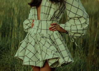 woman in white and black stripe dress standing on green grass field during daytime