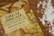A cookbook titled 'Great Bread!' lies on a wooden countertop beside scattered flour. The book cover features images of various types of bread, hinting at its content about making different kinds of bread. The scattered flour adds a baking context to the scene.