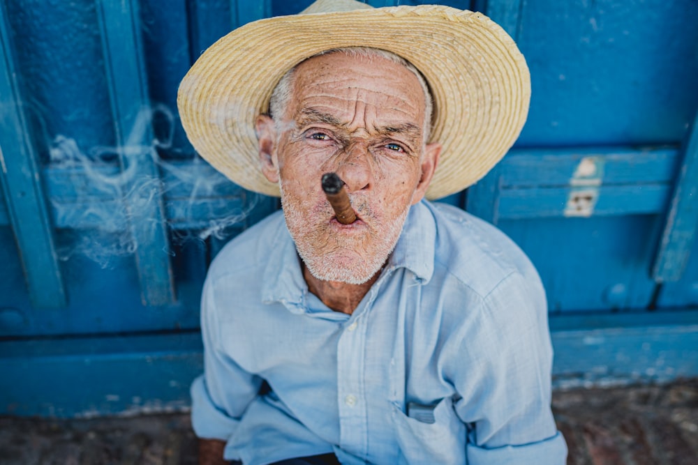 homme en chemise bleue portant un chapeau de paille marron