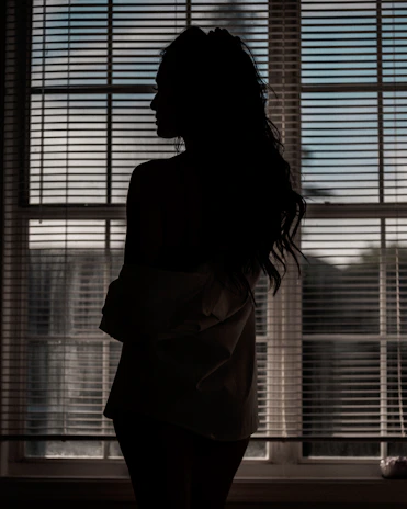A quiet moment of reflection by a window with soft charcoal shadows.