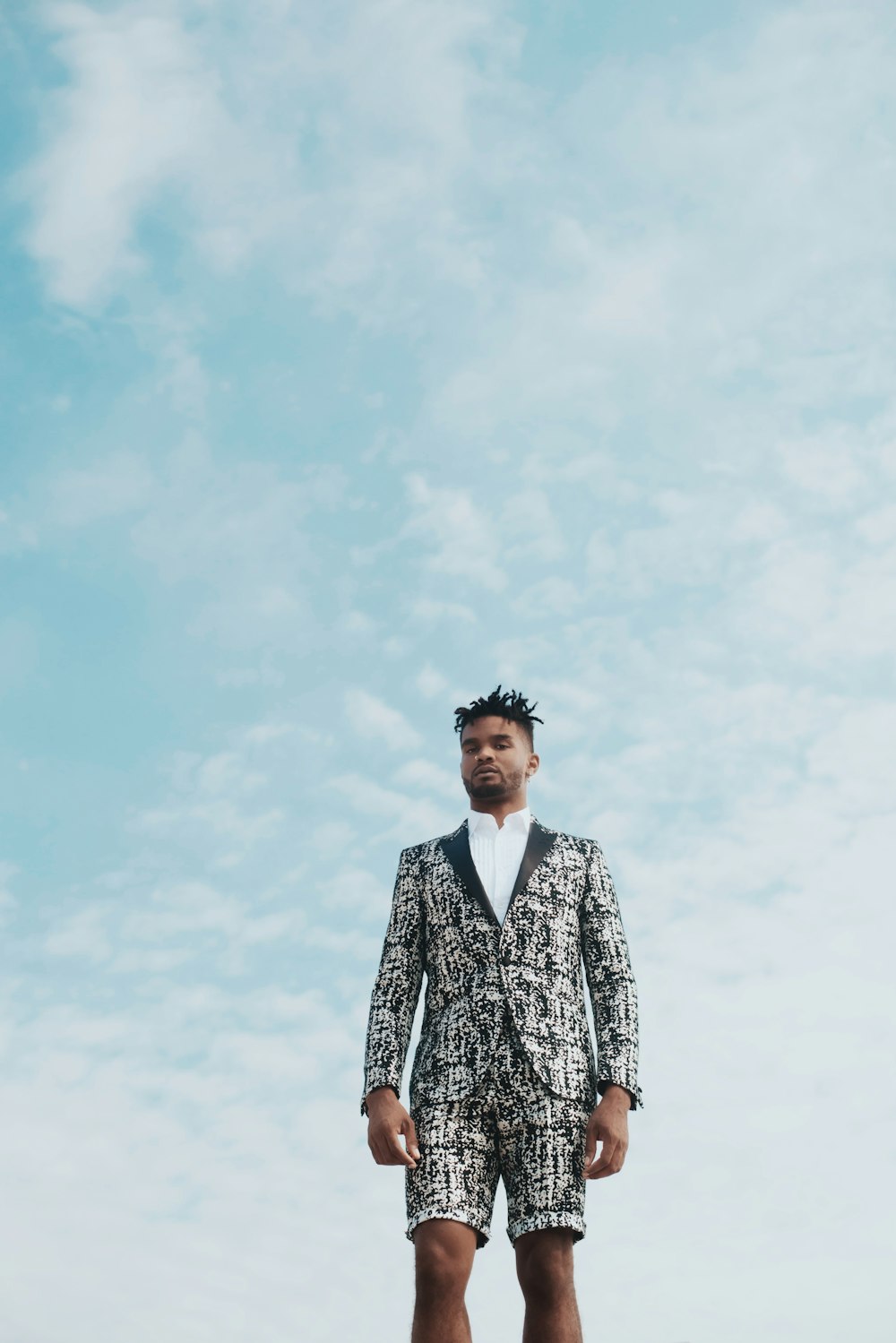 man in black and white floral suit standing under white clouds during daytime