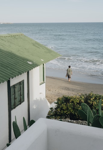 woman in white dress walking on beach during daytime