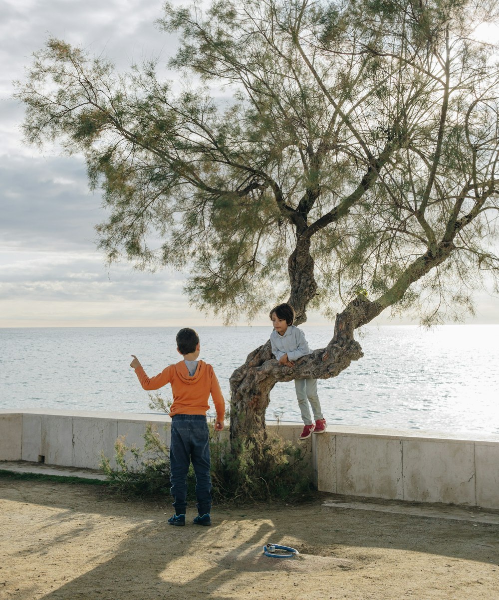 man in orange shirt standing near body of water during daytime