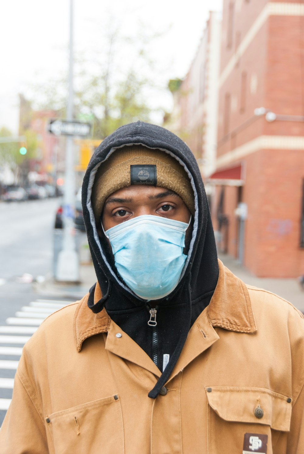 person in brown coat wearing black mask