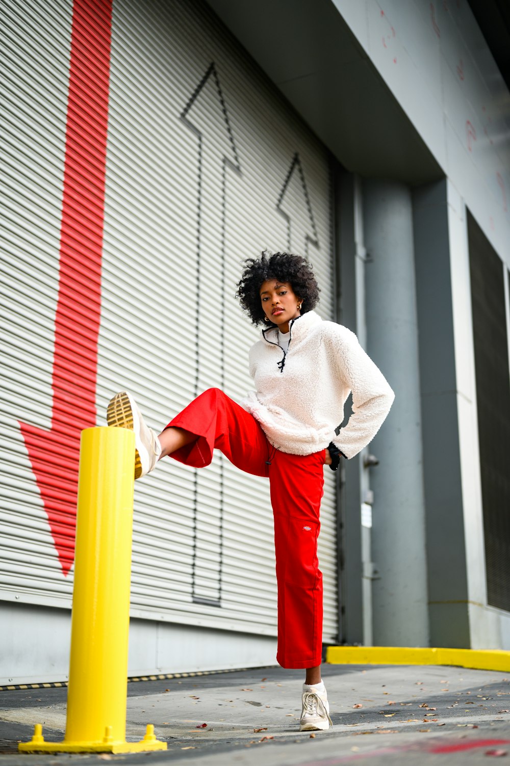 woman in white long sleeve shirt and red skirt standing beside white and red striped wall