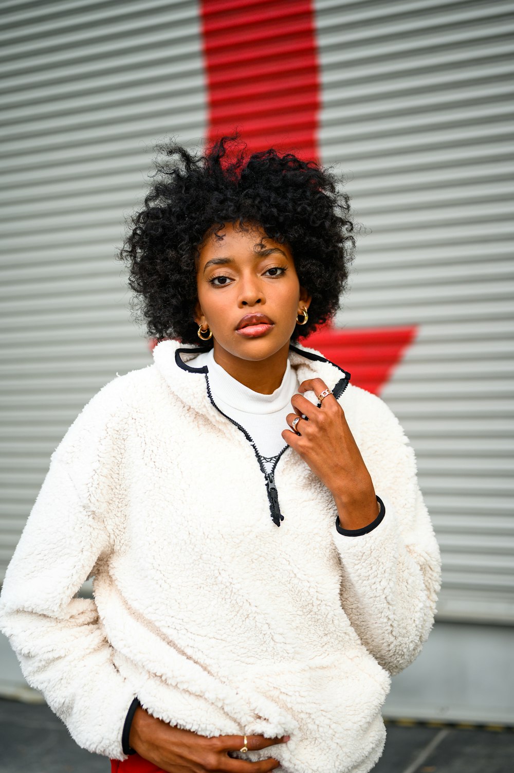 woman in white sweater standing near white wall