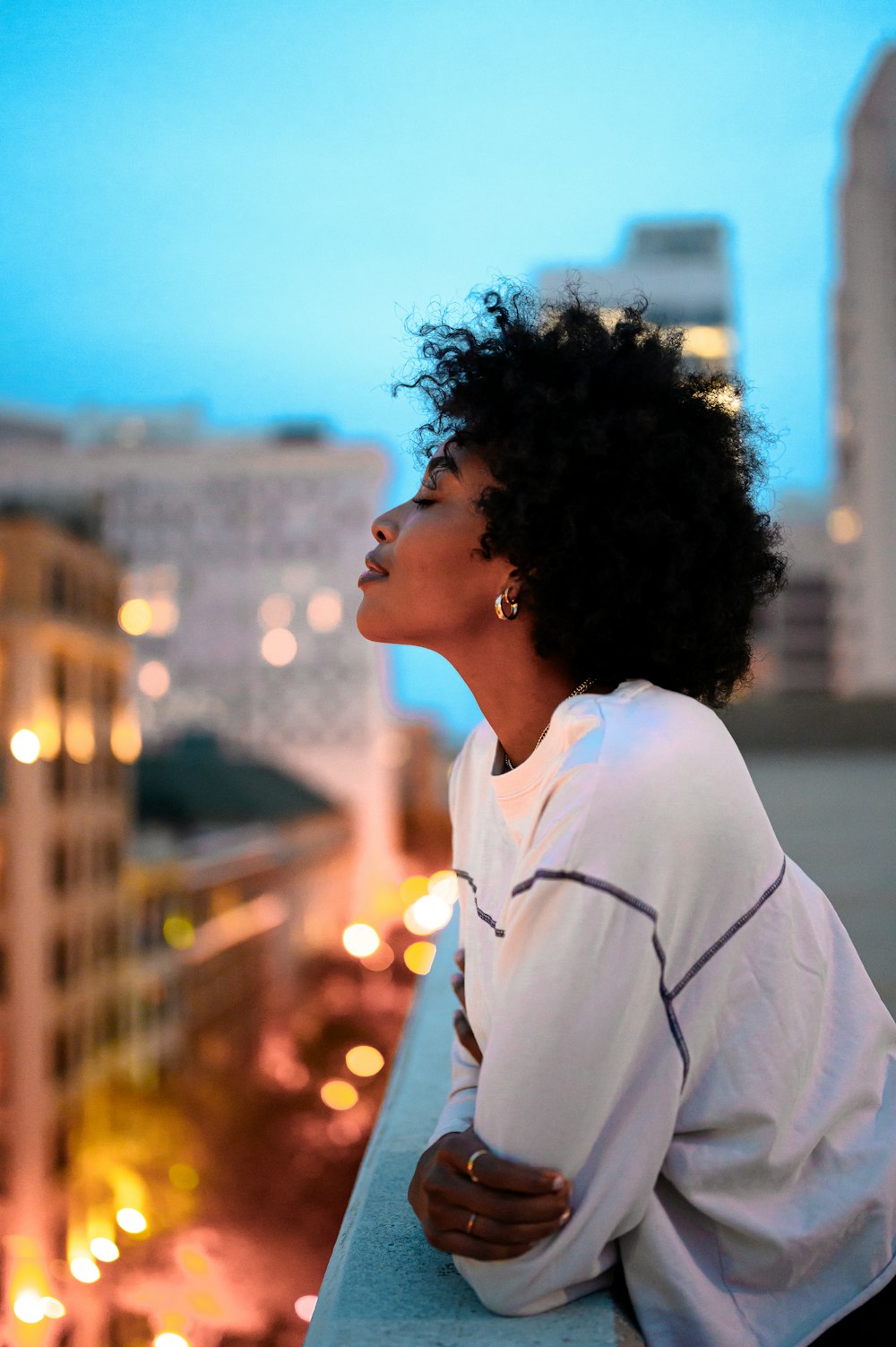 donna in camicia con colletto bianco che guarda la città durante la notte