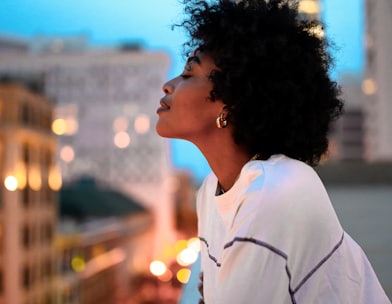 woman in white collared shirt looking at the city during night time