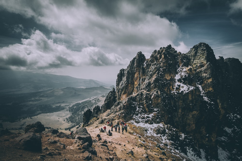 people walking on rocky mountain under cloudy sky during daytime