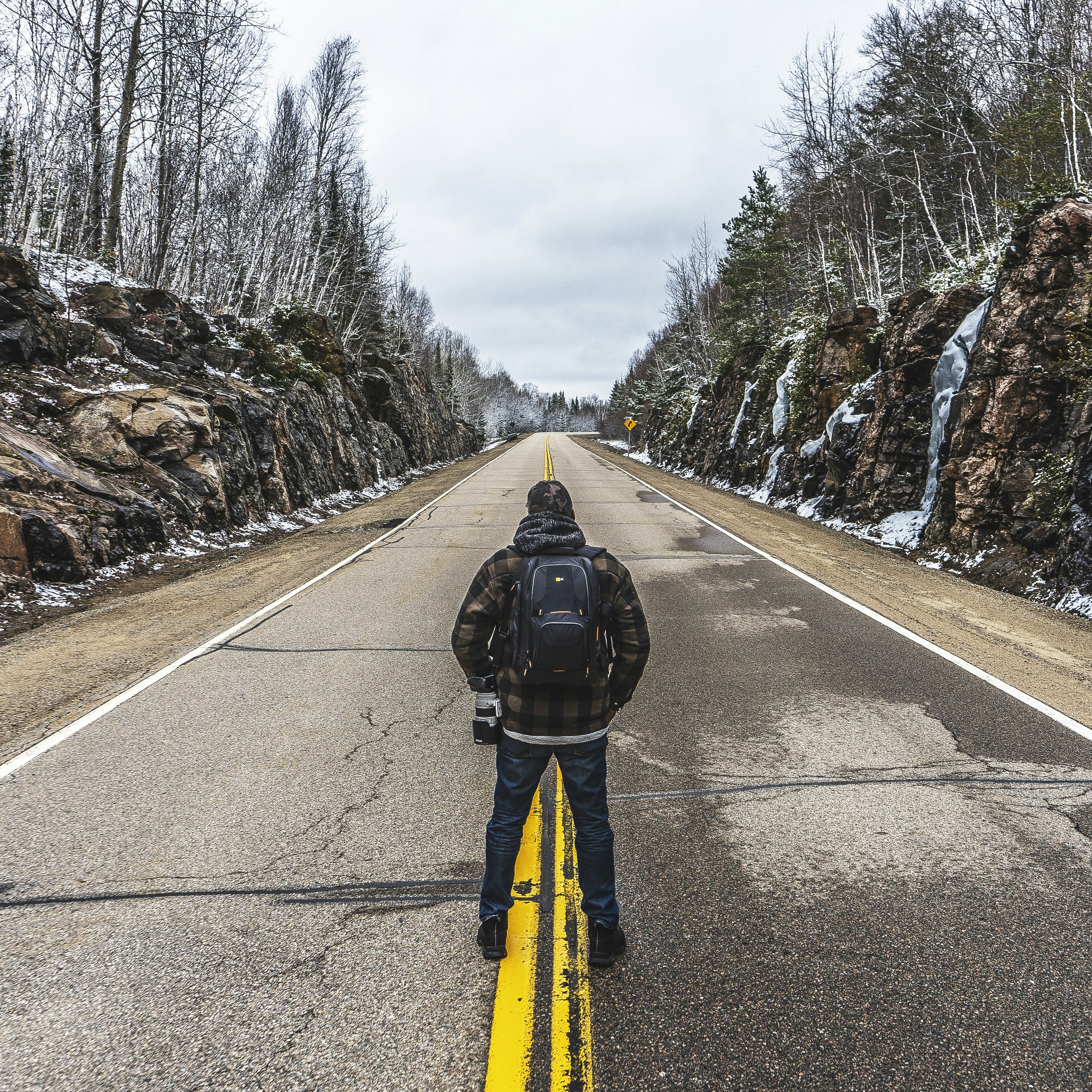 man in yellow jacket and black pants walking on road during daytime