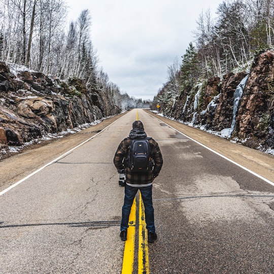 man in yellow jacket and black pants walking on road during daytime in Muskoka Canada