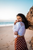 A joyful woman twirling on the beach wearing a bright red bikini, sunlight catching the fabric.