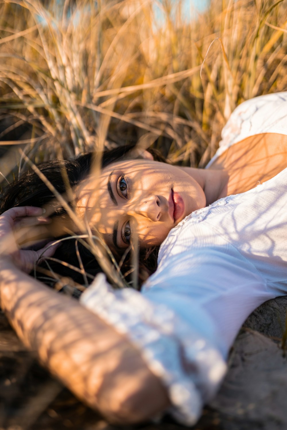 donna in camicia bianca sdraiata su erba marrone