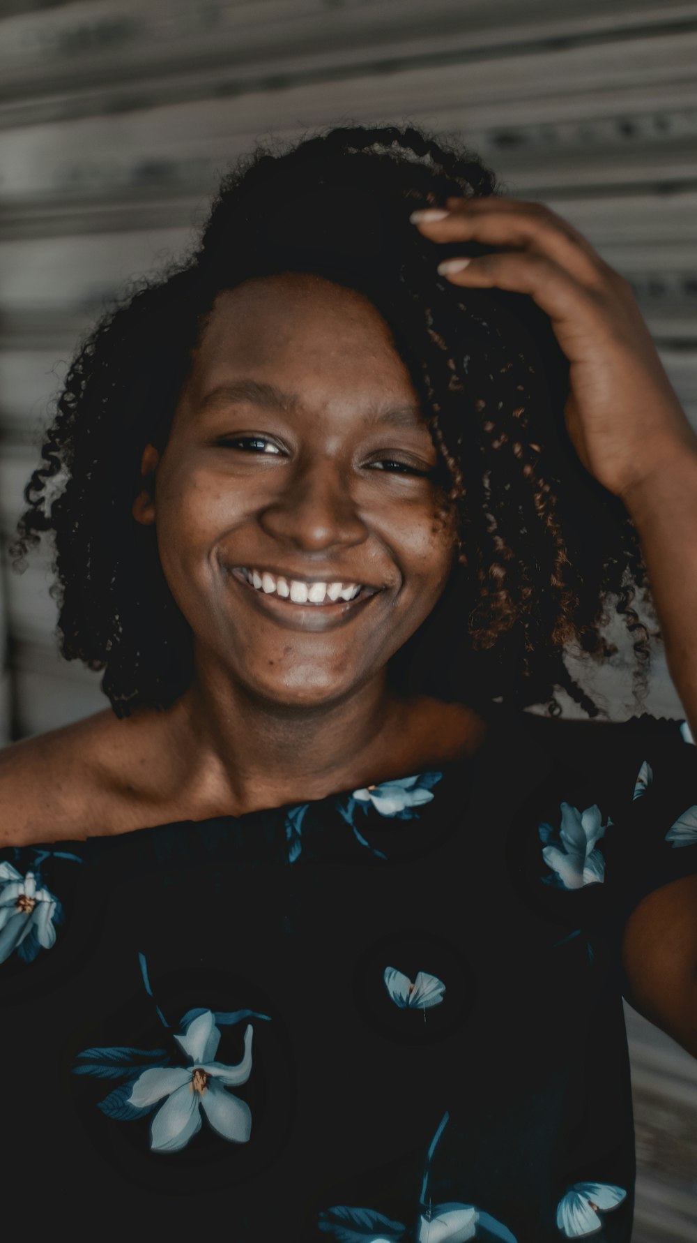 woman in blue and black floral dress smiling