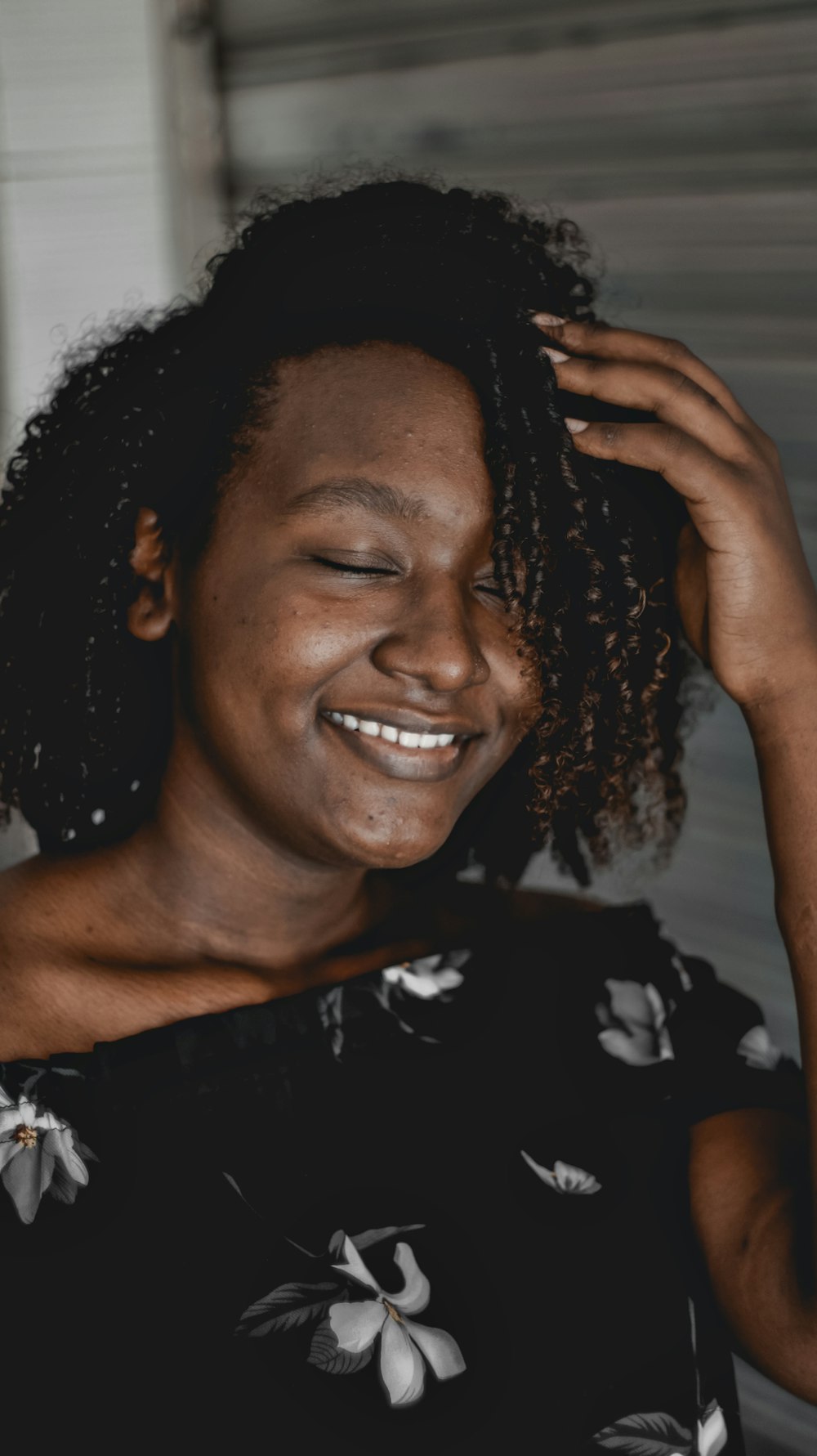 smiling woman in black and white floral shirt