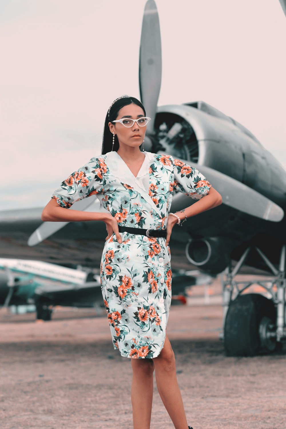 woman in white red and blue floral dress standing near airplane