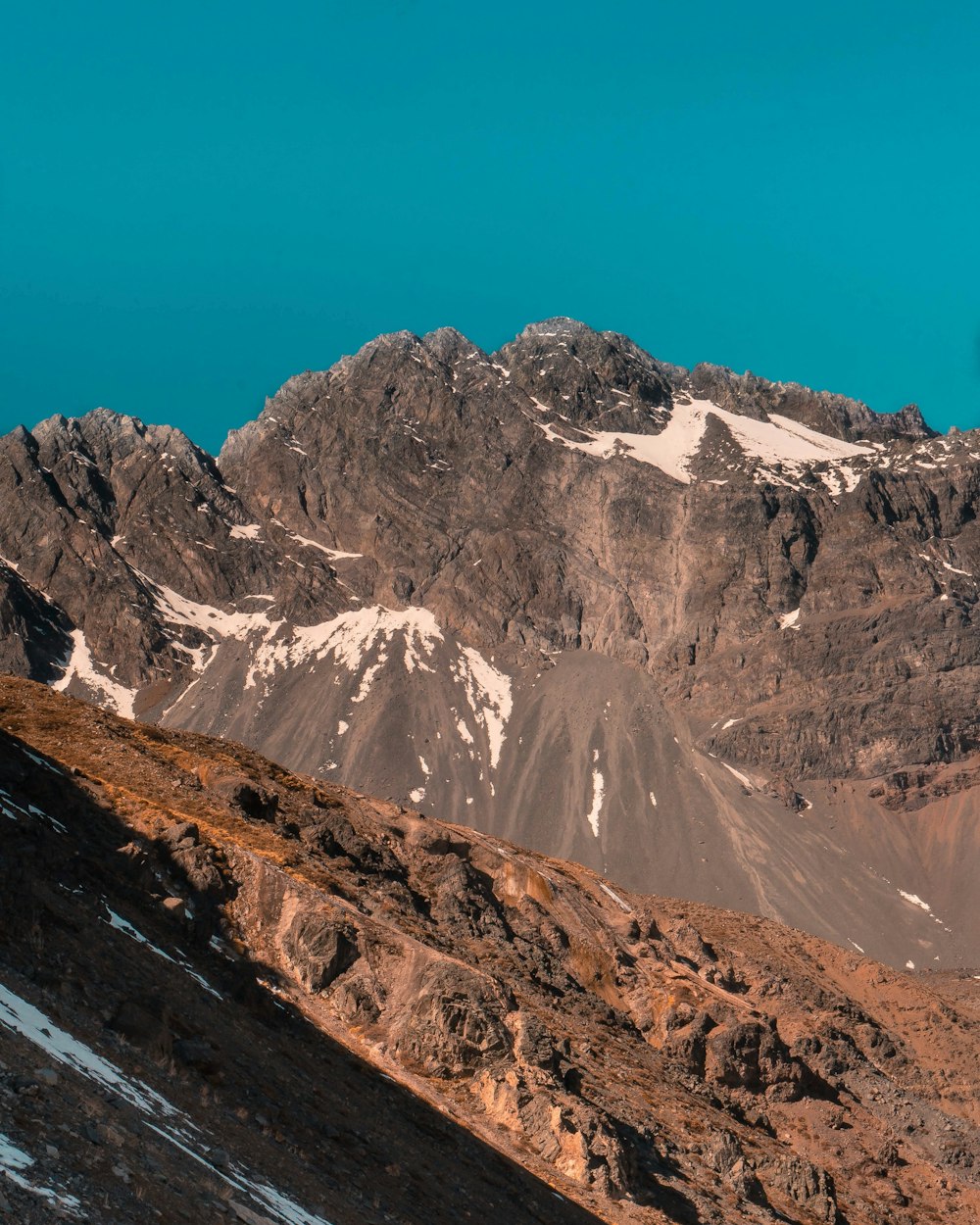 montanhas marrons e brancas sob o céu azul durante o dia