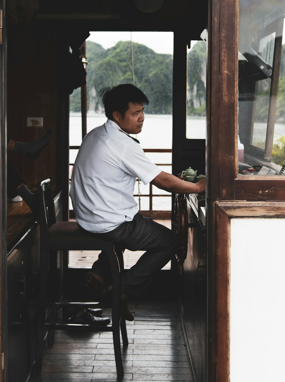 man in white dress shirt sitting on brown wooden chair