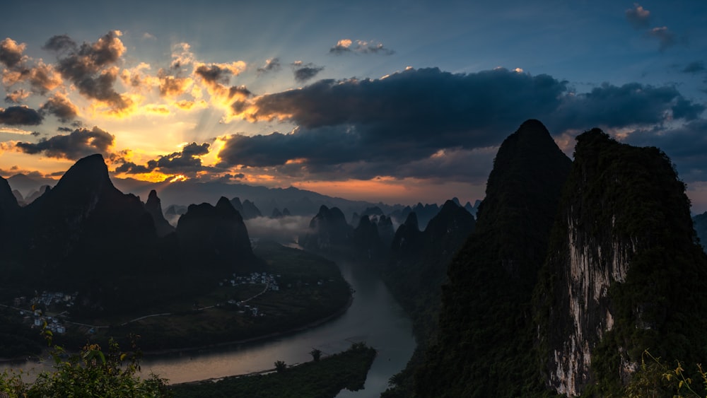 silhouette of mountain under cloudy sky during sunset