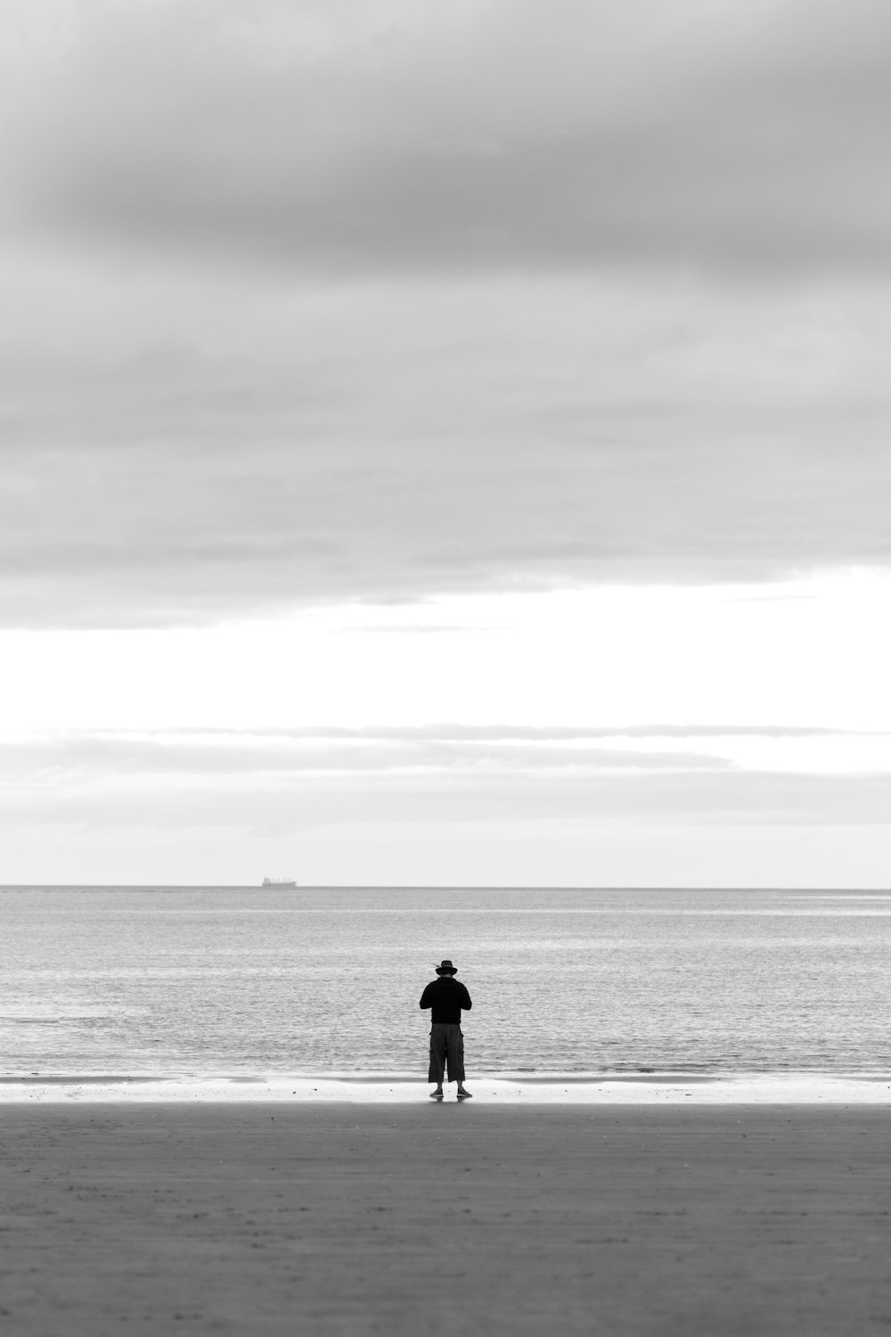 grayscale photo of man and woman standing on beach