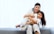 2 women sitting on gray couch