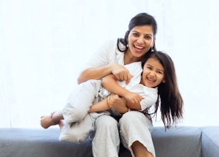 2 women sitting on gray couch