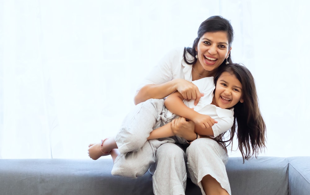 2 women sitting on gray couch